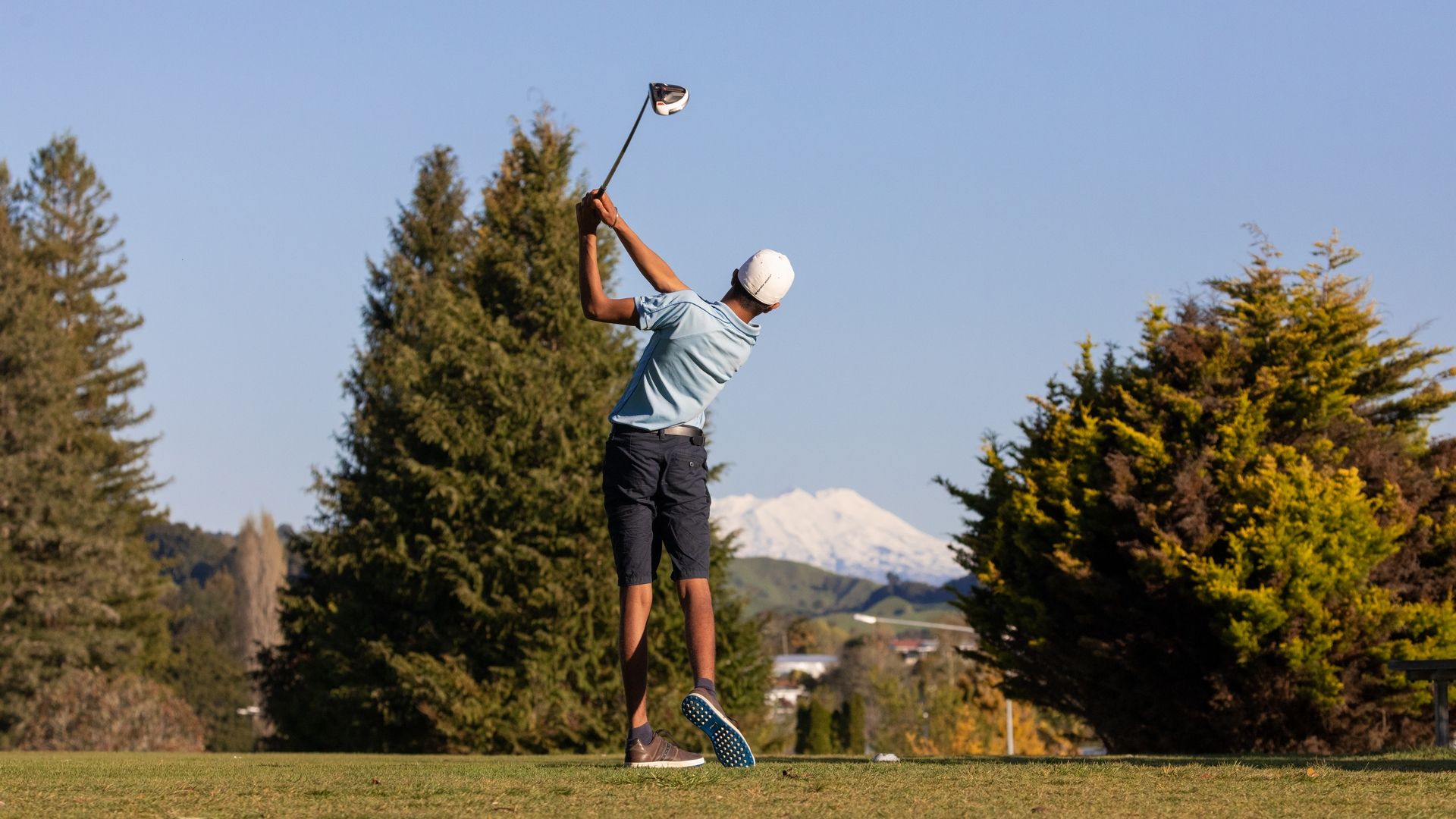 Young golfer teeing off at Taumarunui Golf Club with Mt Ruapehu in the background - Visit Ruapehu.jpg